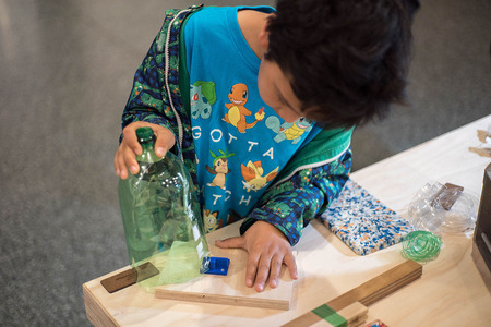 A child uses a REBOOT device for turning waste plastic into filament